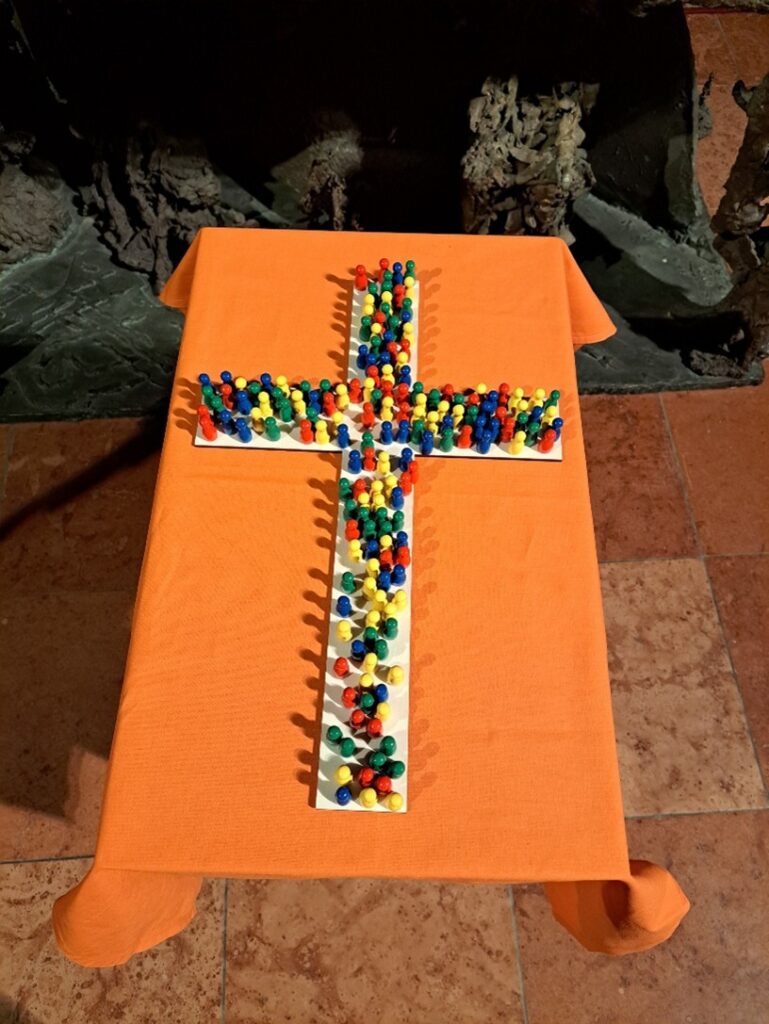 Spielsteine auf einem Kreuz, symbolisch als ein gemeinsames Zeichen für das Zusammenwirken in der neuen Pfarre zur Sel. Sr. Restituta
